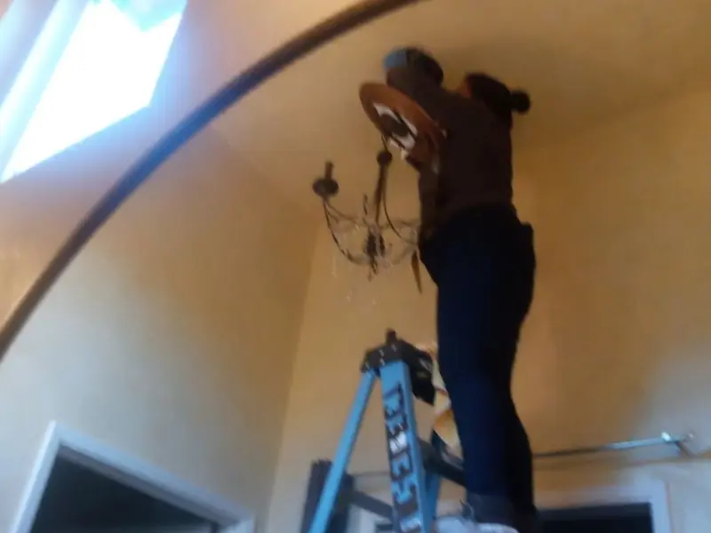 Electrician installing a chandelier in a Westfield residence